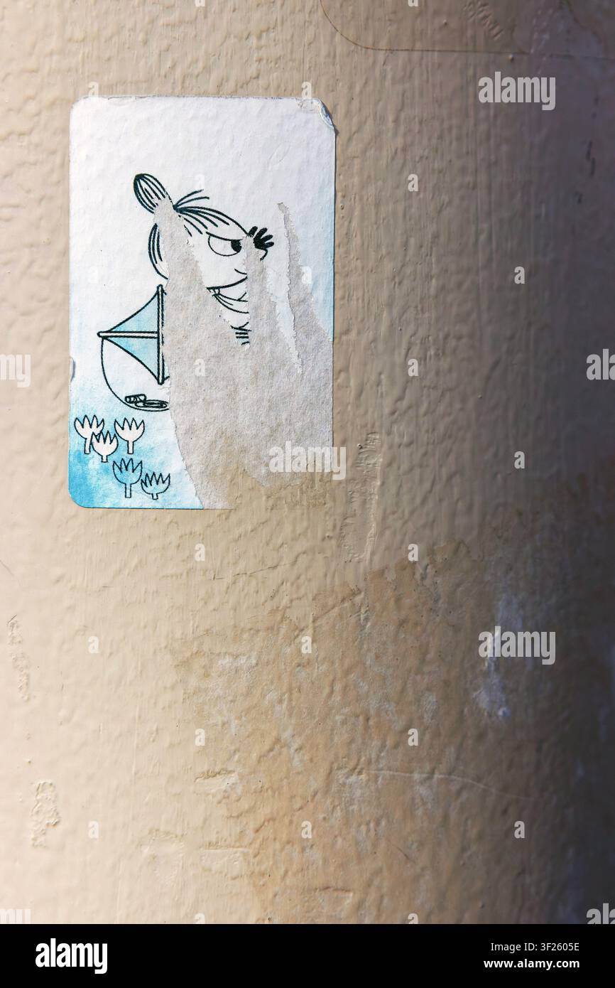 Tallinn, Estonia, August 31, 2024: Weathered sticker depicting Little My, a character from the Moomins, pasted on a rough beige wall Stock Photo