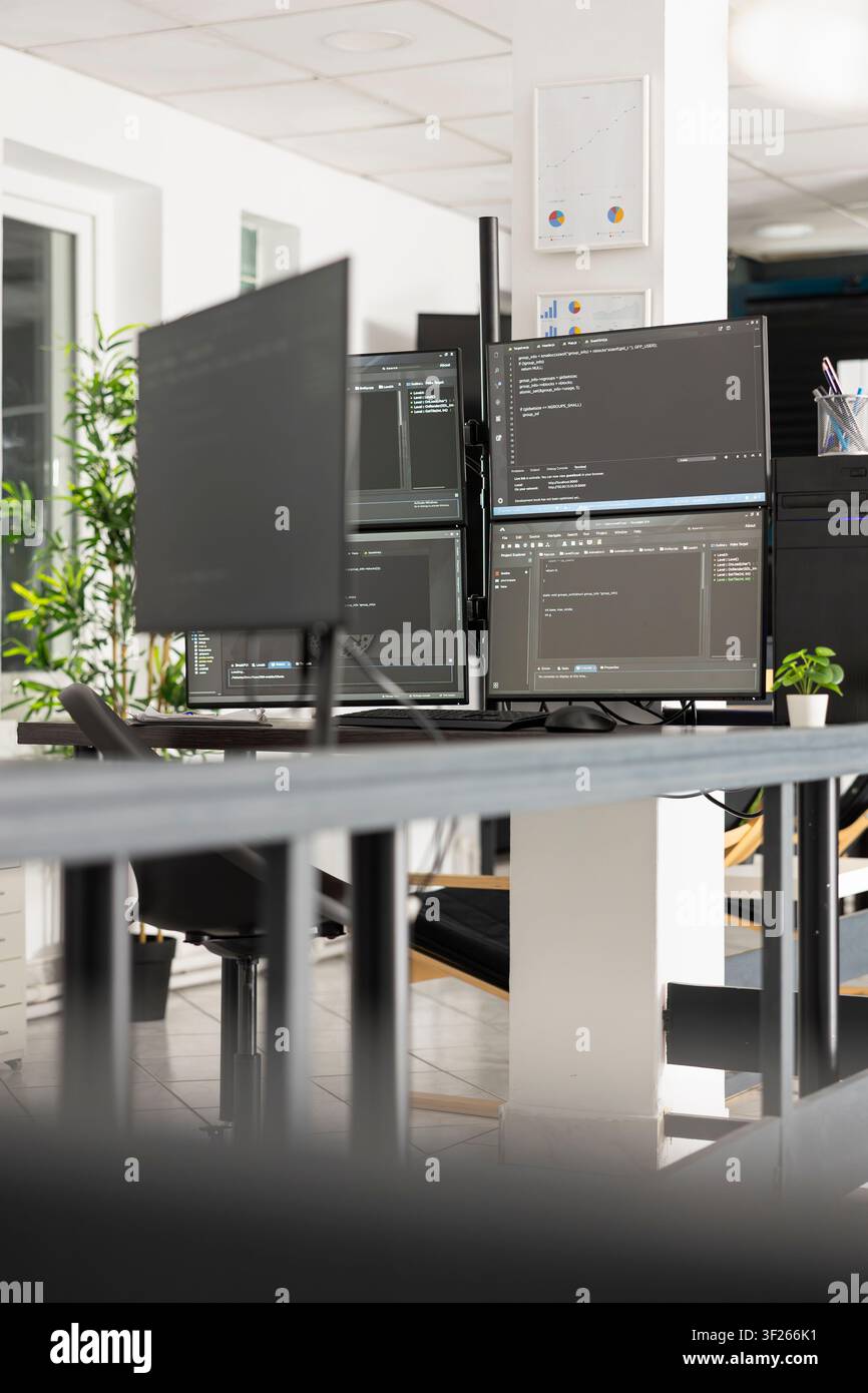 Multimonitor setup showing html scripts in vacant, bright and modern office environment, reflecting software development and advanced technology. Unoccupied workspace having computer screens with code Stock Photo
