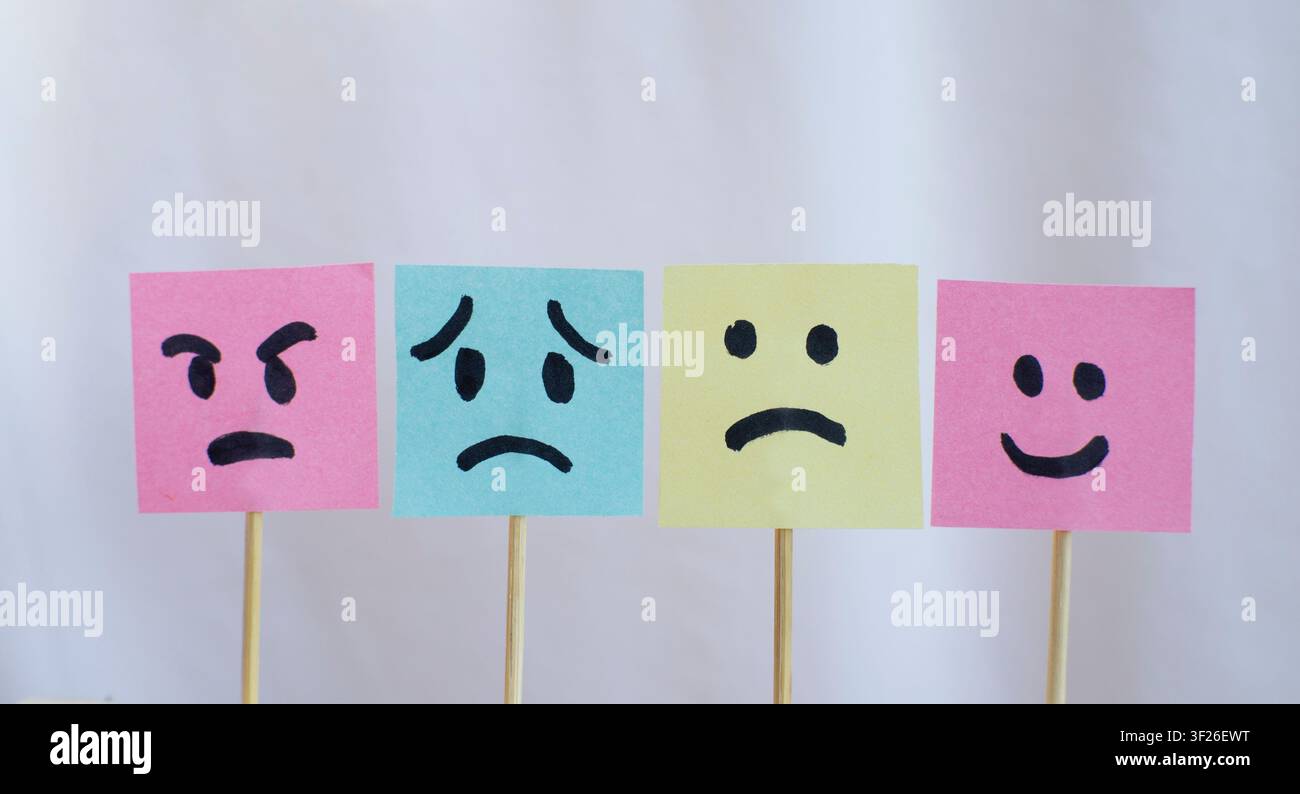 Four Emotion Face Sticky Notes on White Fabric Background Stock Photo