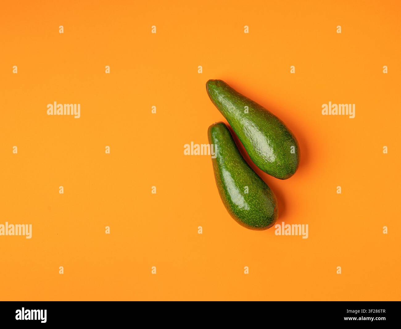 Avocado Isolated, Whole Avokado Set, Two Green Avocados Pile, Fresh Alligator Pear, Guacamole Ingredient, Long Avocado Fruit on Orange Background Stock Photo