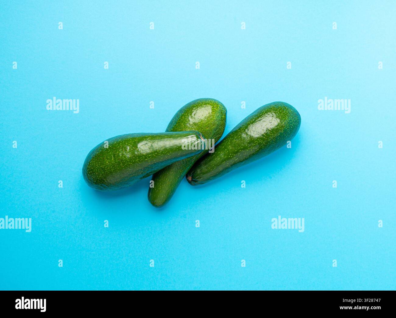 Avocado Isolated, Whole Avokado Set, Three Green Avocados Pile, Fresh Alligator Pear, Guacamole Ingredient, Long Avocado Fruit on Blue Background Stock Photo