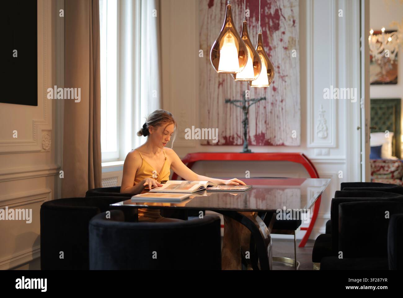 Stylish woman sitting at a table reading a book Stock Photo