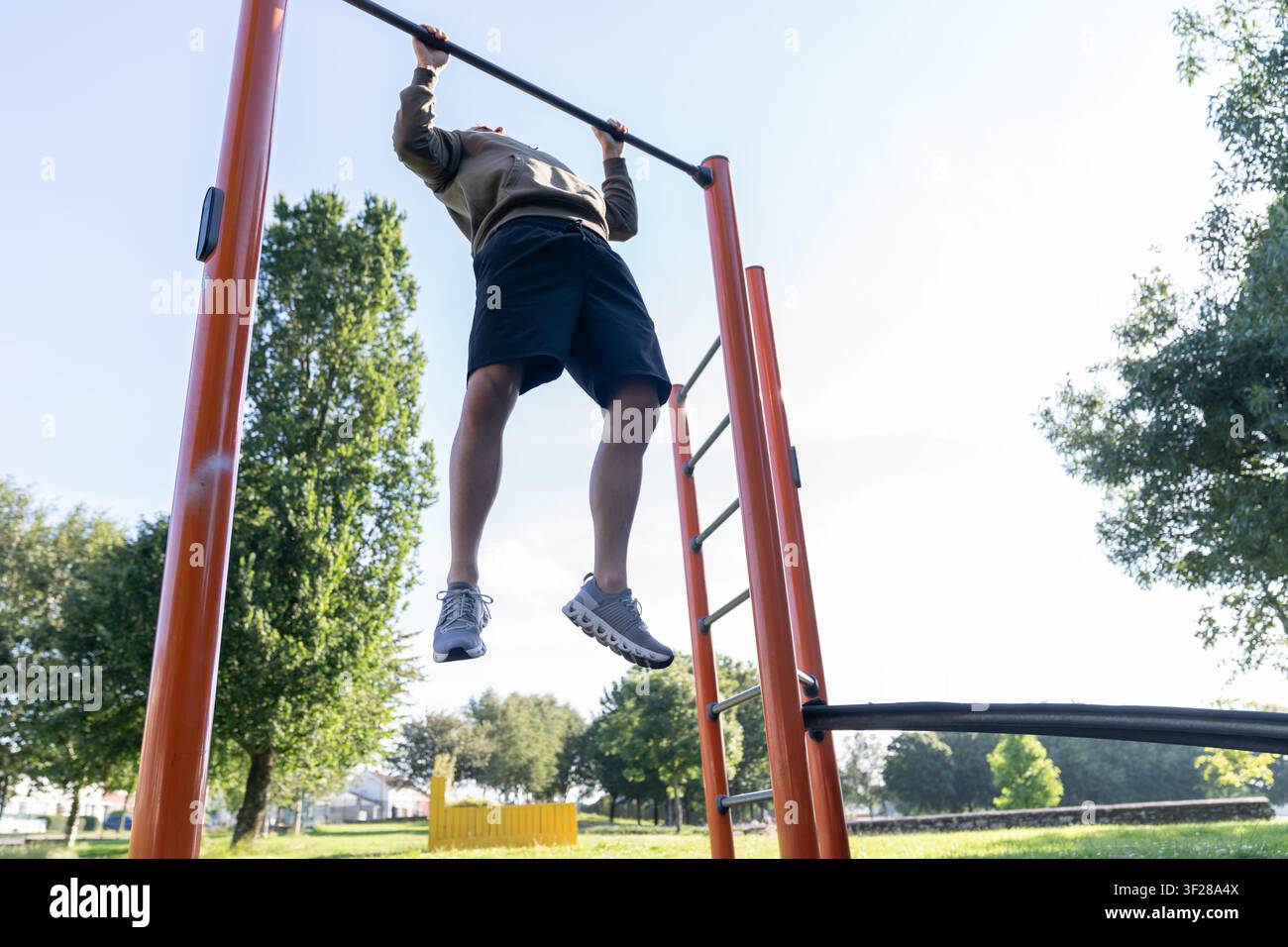 Man doing pullups on outdoor exercise bar Stock Photo