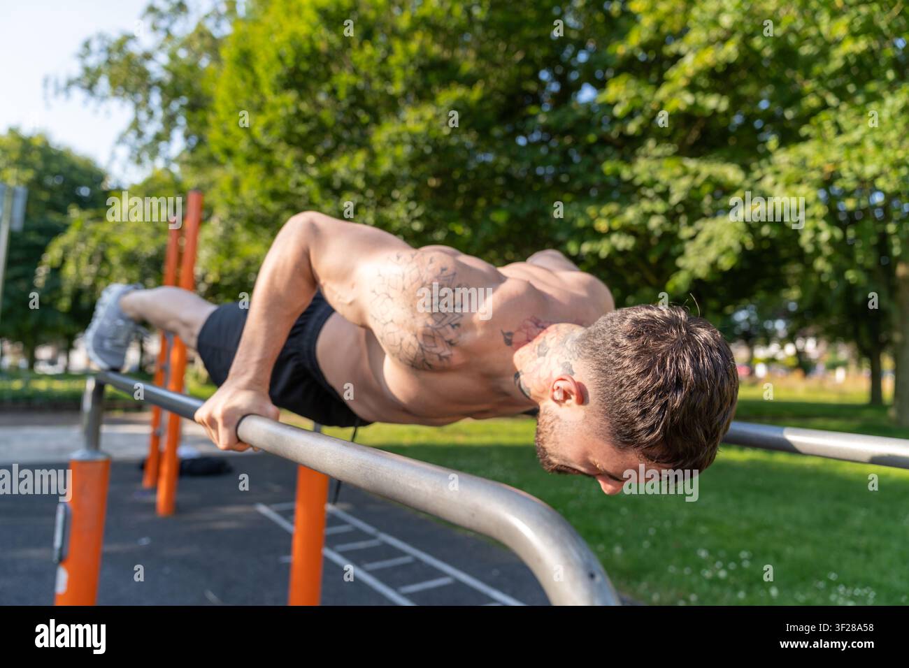 Athletic man doing pushups on parallel bars outdoor Stock Photo