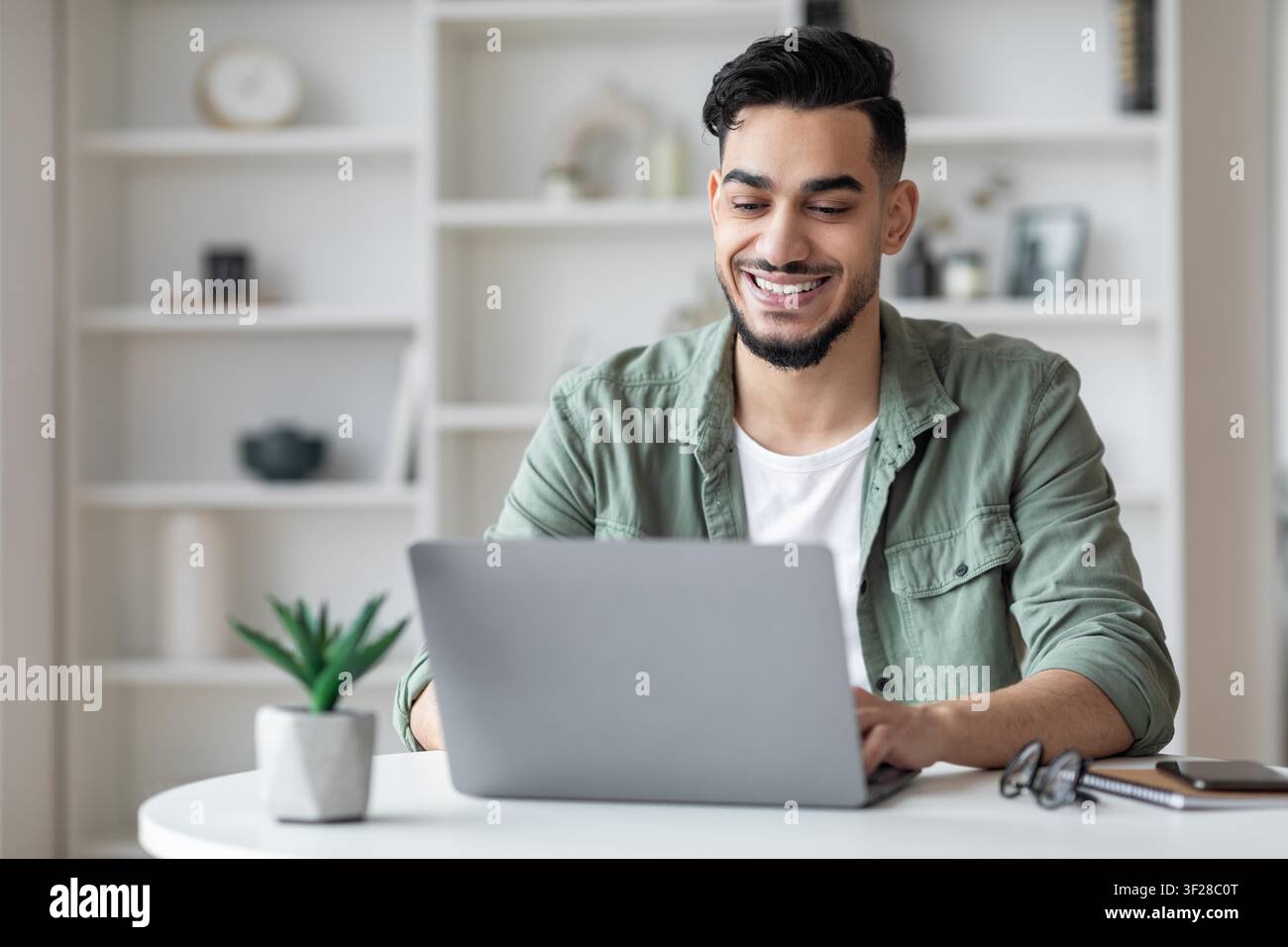 Smiling Young Man Working On Laptop At Home Office, Business Concept Stock Photo