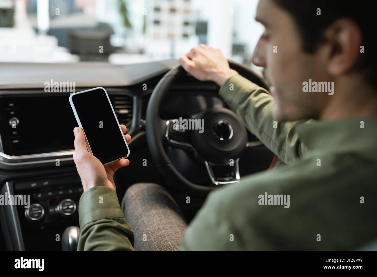 Unrecognizable Man Using Smartphone While Driving A Car, Focused On Mobile Device Stock Photo