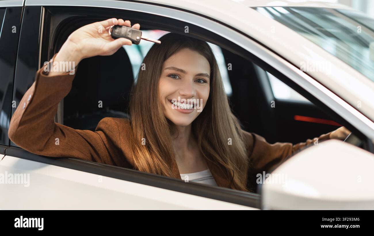Happy Young Woman Holding Car Key Inside New Vehicle, Excited About Purchase, Business Concept Stock Photo