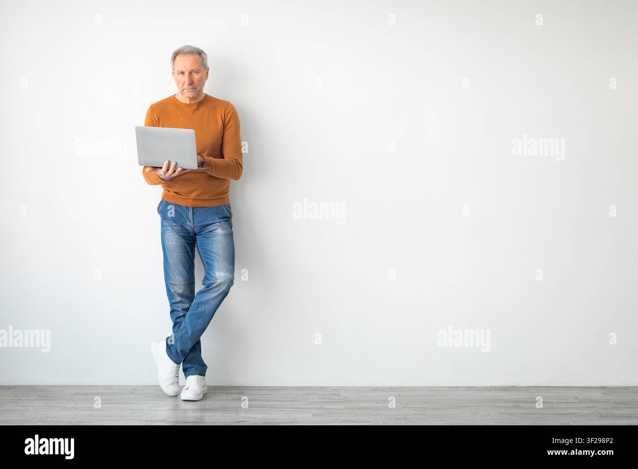 Elderly Caucasian Man Using Laptop While Standing, Home Office Concept Stock Photo