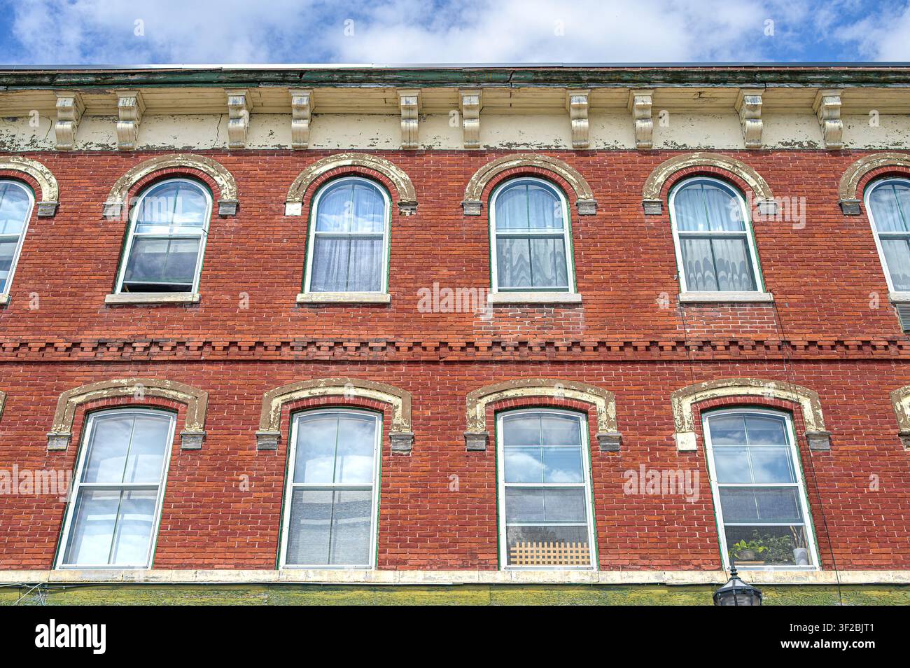 Historic red brick building facade with arched windows, decorative cornice, and classic architectural details Stock Photo