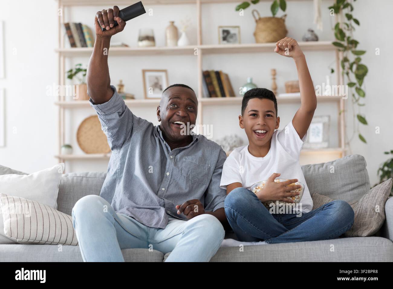 Leisure With Grandpa. Senior African Man Watching Sports On Tv With Grandson Stock Photo