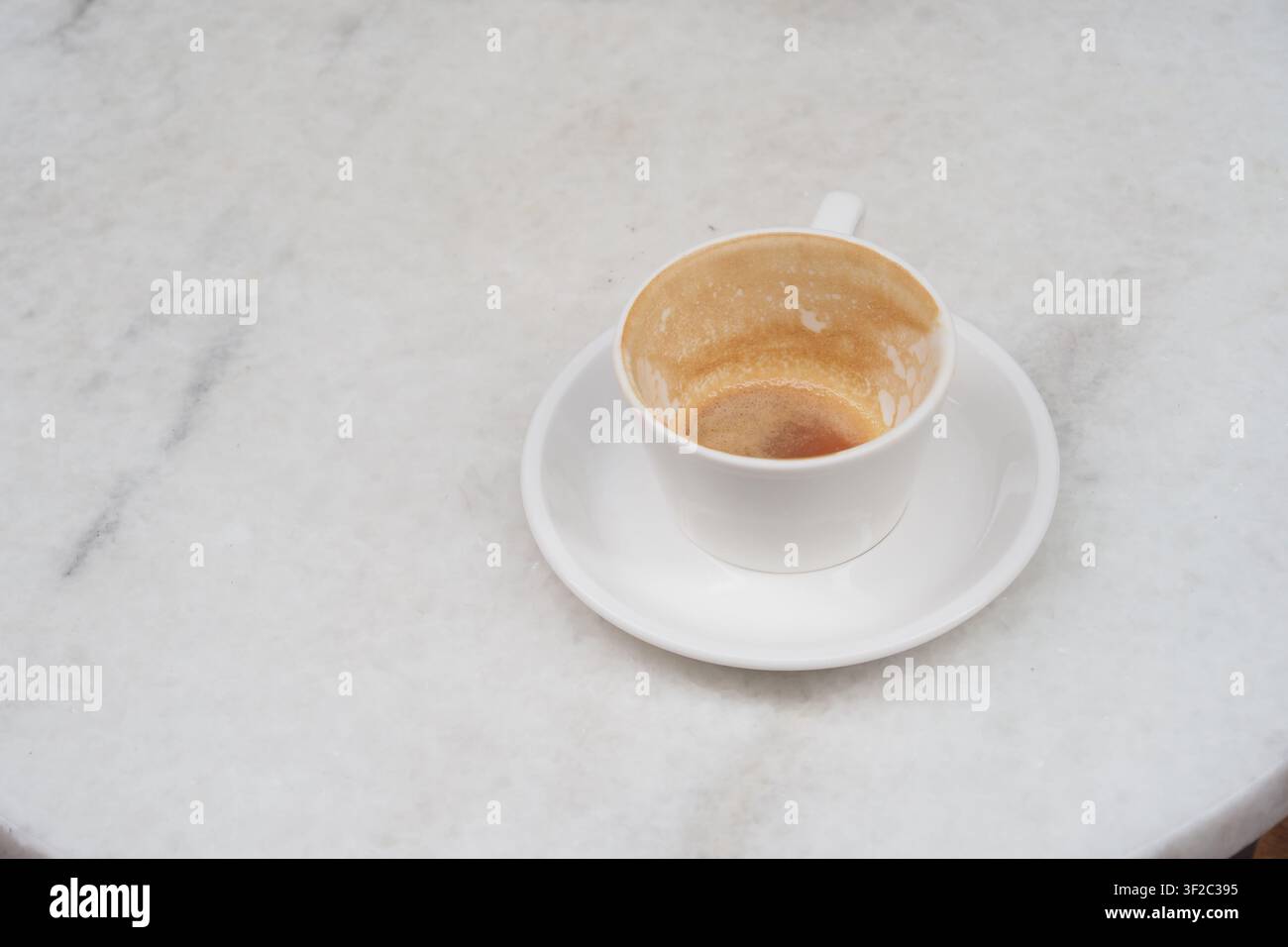 Cup sits empty on a white table after enjoying coffee Stock Photo