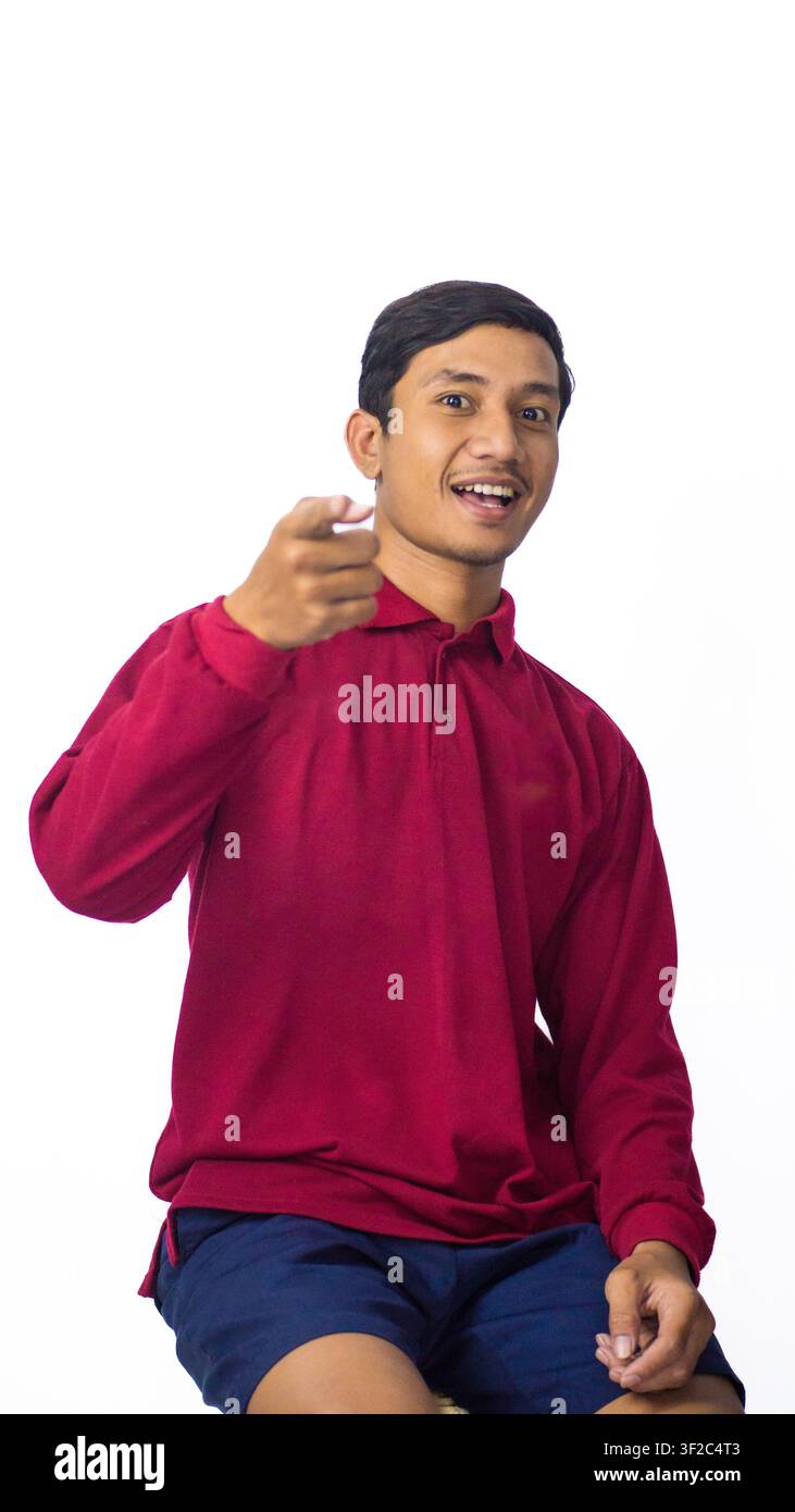 Smiling Asian male model wearing traditional shirt showing pointing forward on white studio background. Stock Photo