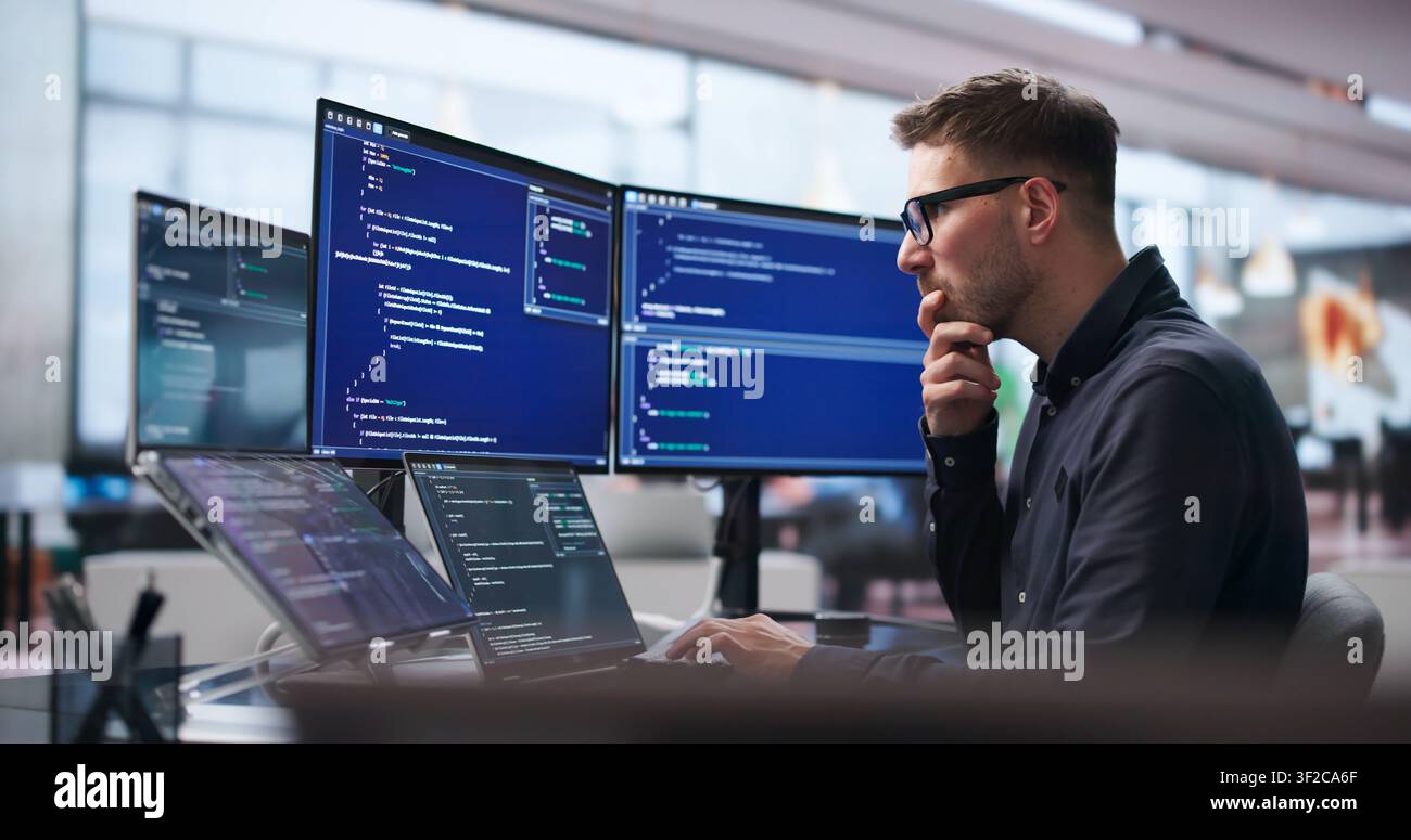 Young Software Engineer Uses Laptop And Touchscreen To Develop Secure Algorithms. Stock Photo