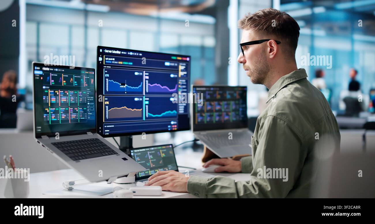 Young IT Specialist Monitors Real-time Network Data On Laptop Screen. Stock Photo