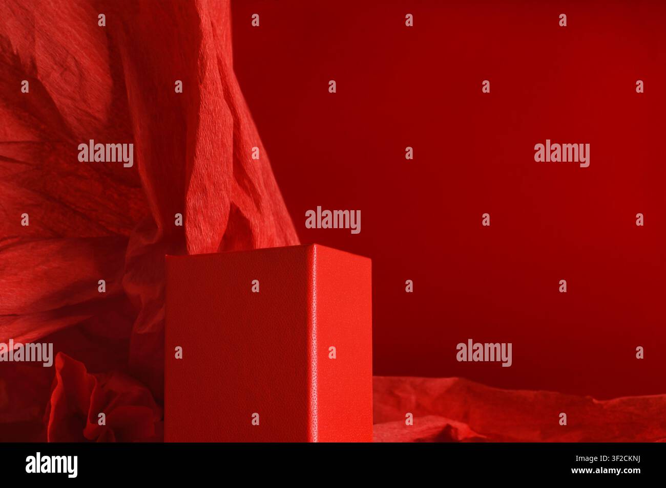 Empty red rectangular podium on dramatic red background with crumpled paper Stock Photo