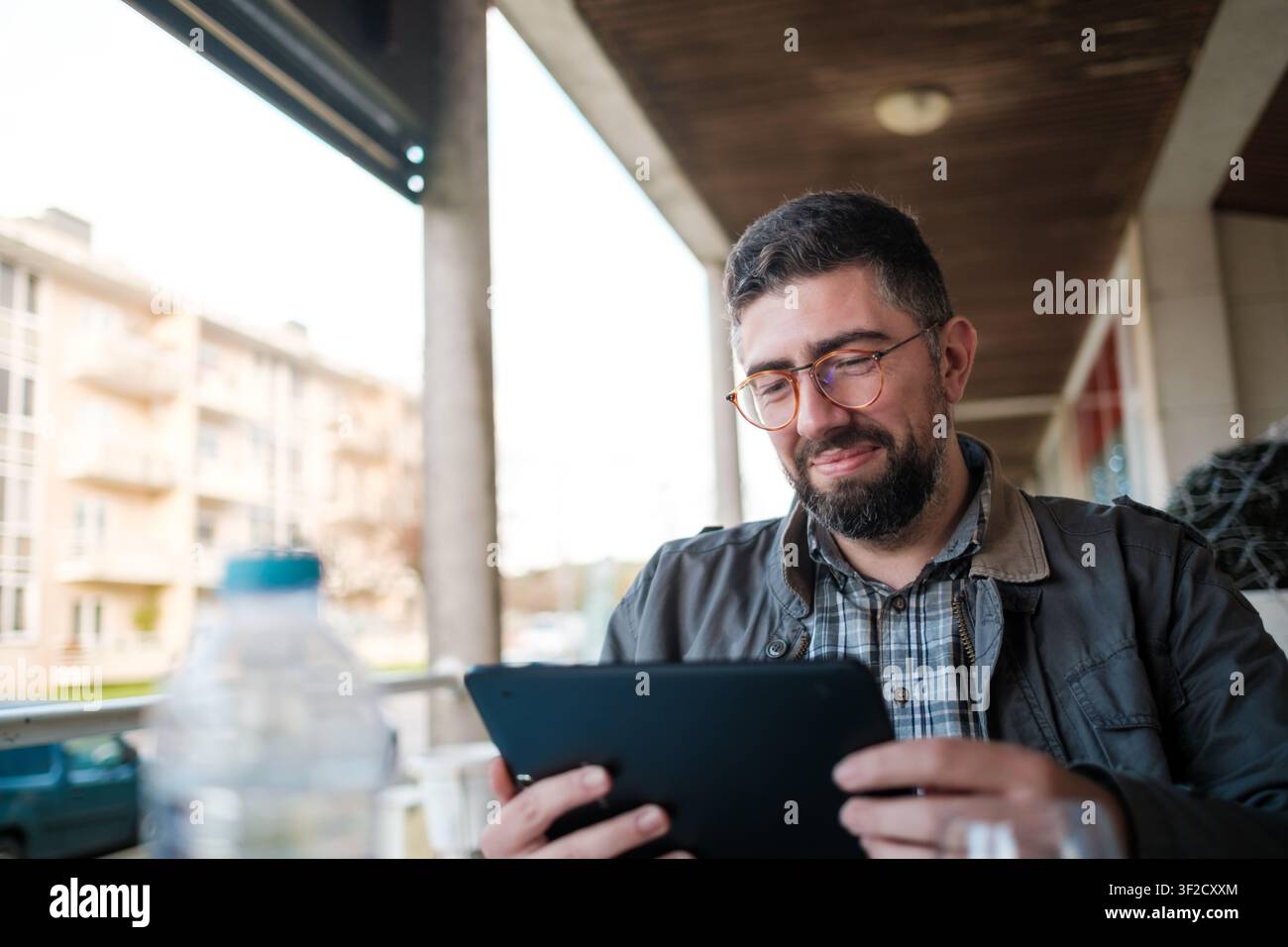 Man smiling, using tablet outdoors, working remotely with modern technology Stock Photo