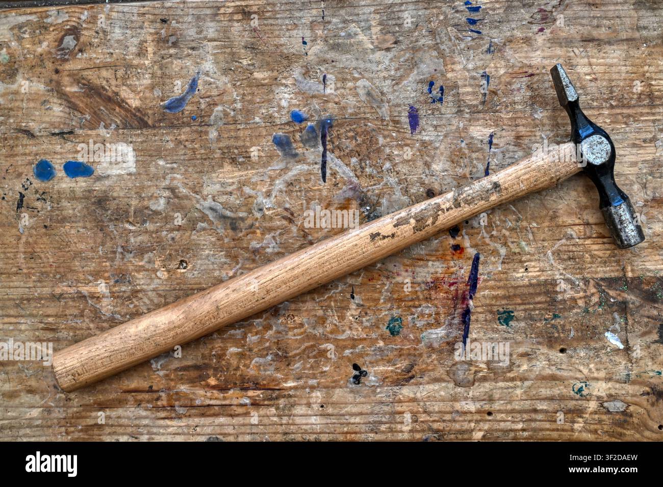 Old hammer on a stained and weathered work bench top Stock Photo
