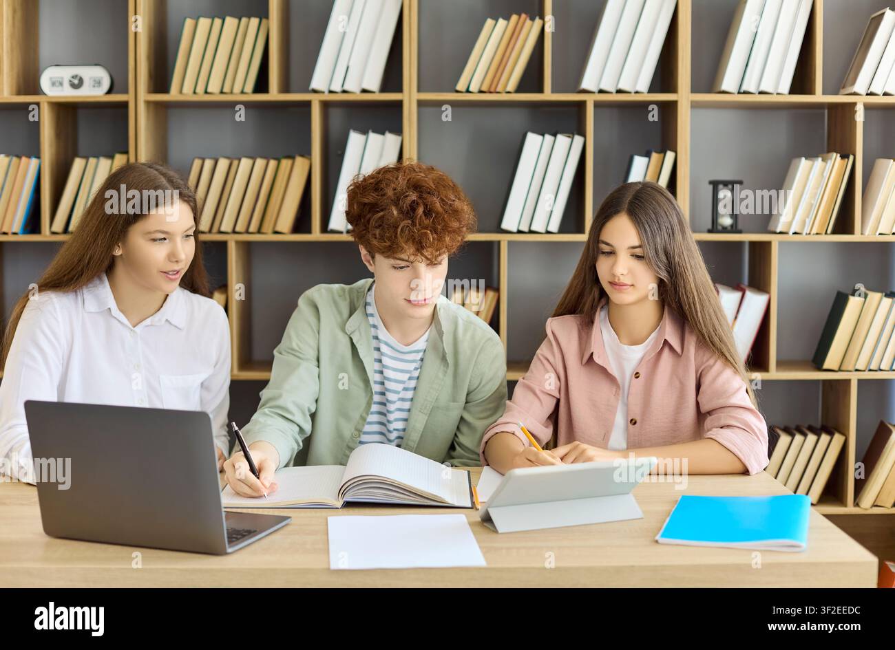 Students studying in library with laptop and tablet, teamwork on modern project Stock Photo