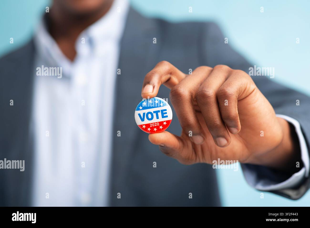 African man holding vote button on blue background Stock Photo