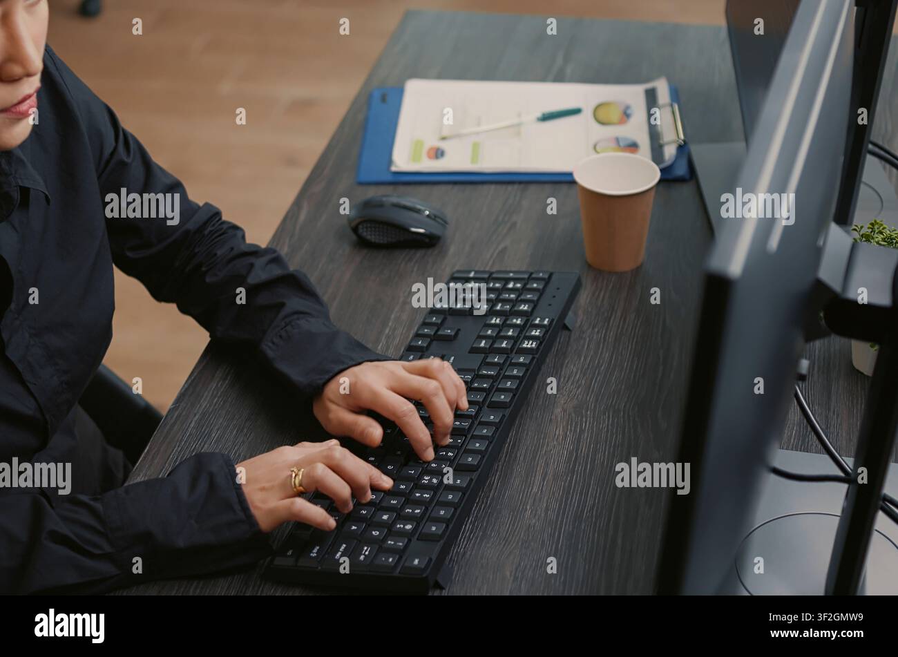 Programmer types source code on a computer keyboard, working at a desk with programming screens, algorithm notes and software development tools. Stock Photo