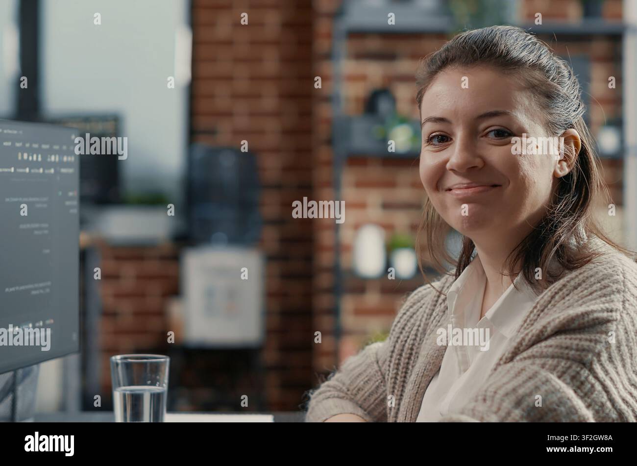 Focused portrait with software developer typing programming language on computer keyboard turning head and smiling at camera around computer screens, showing developer teamwork, source code. Stock Photo