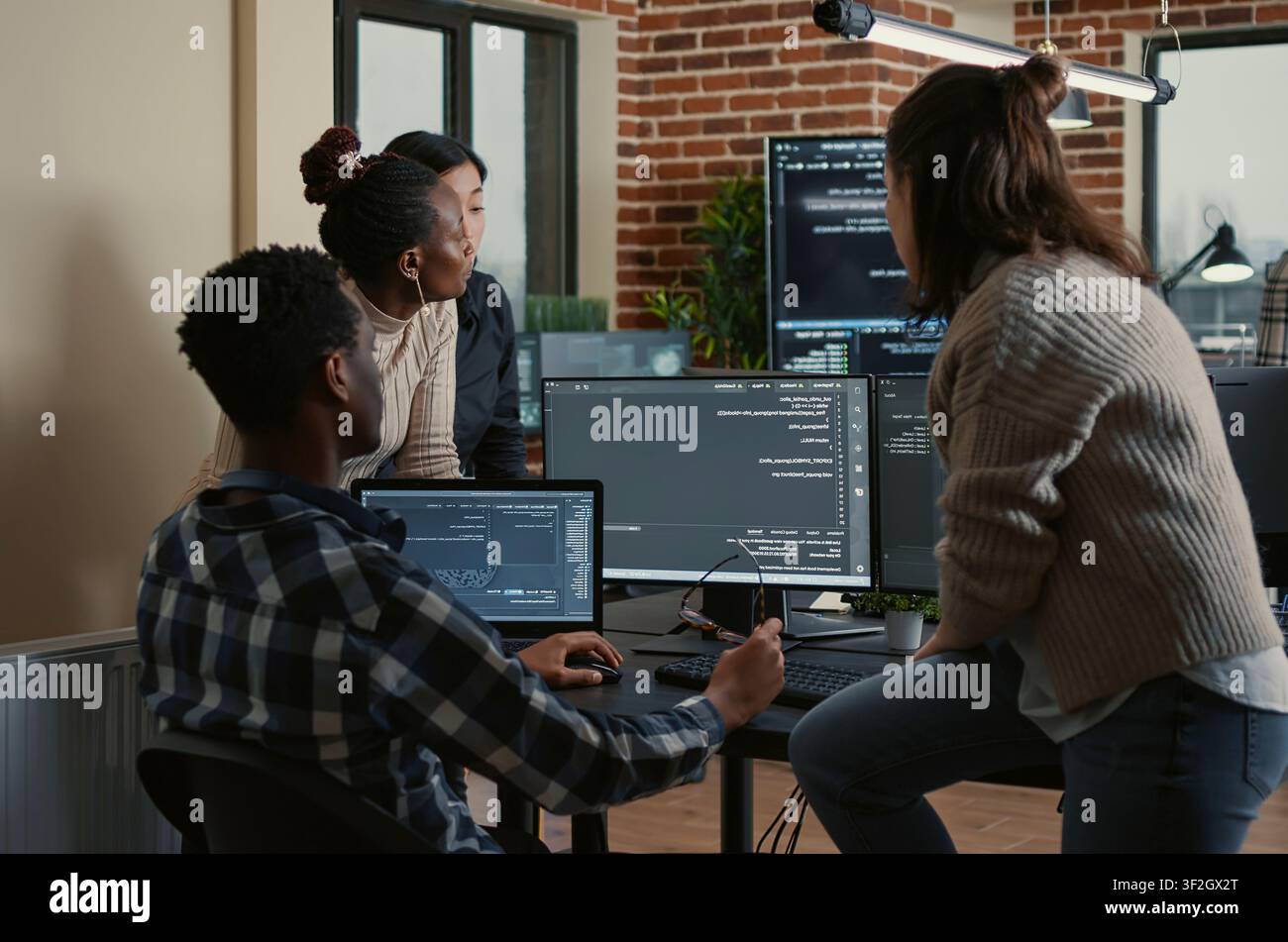 Software developers discuss cloud programming innovation as the rest of the team joins, collaborating on big data and server room computing. Stock Photo