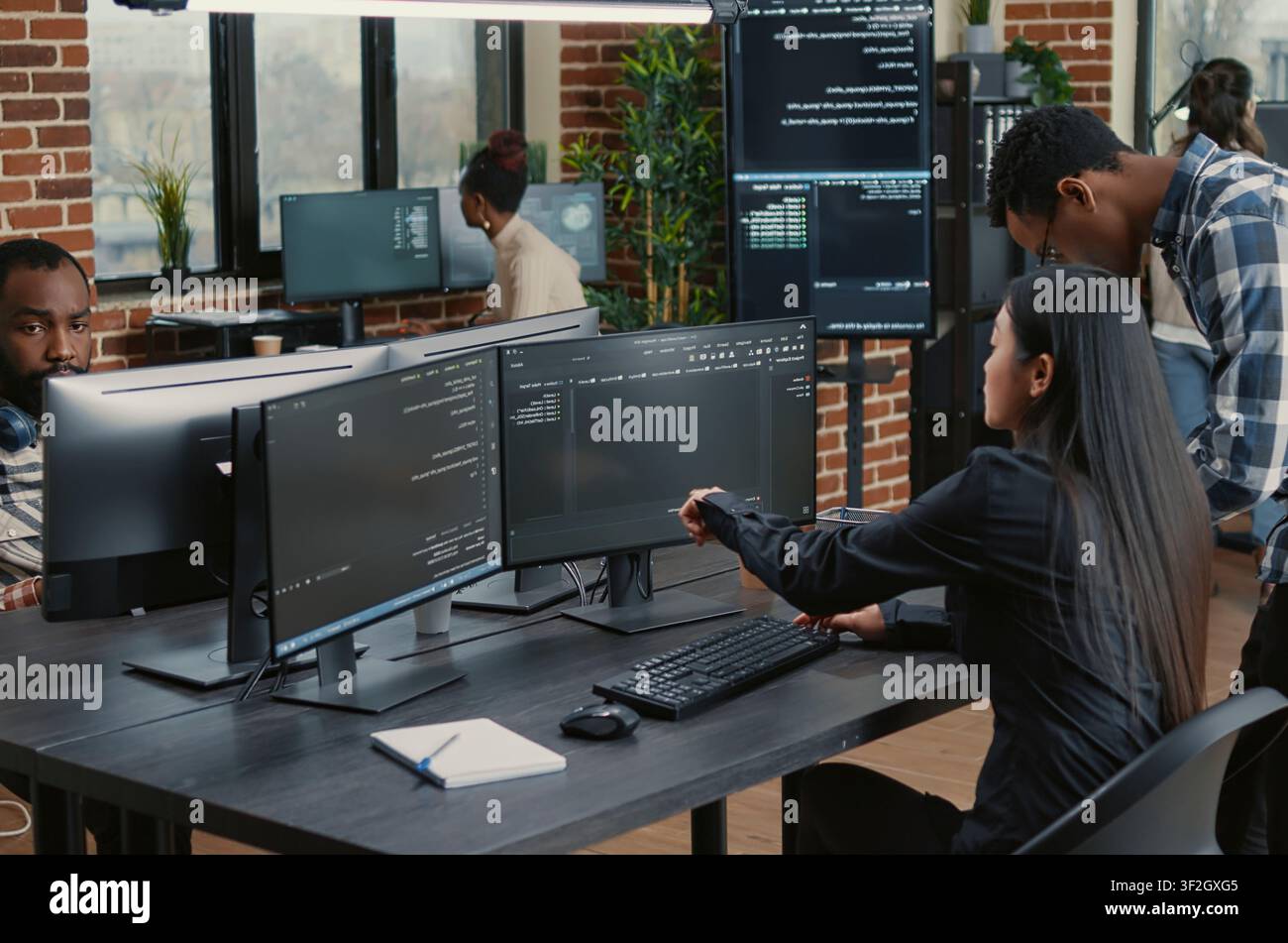 Mixed team of programmers points at screens and compares source code, algorithms and user interface details during a software project review. Stock Photo