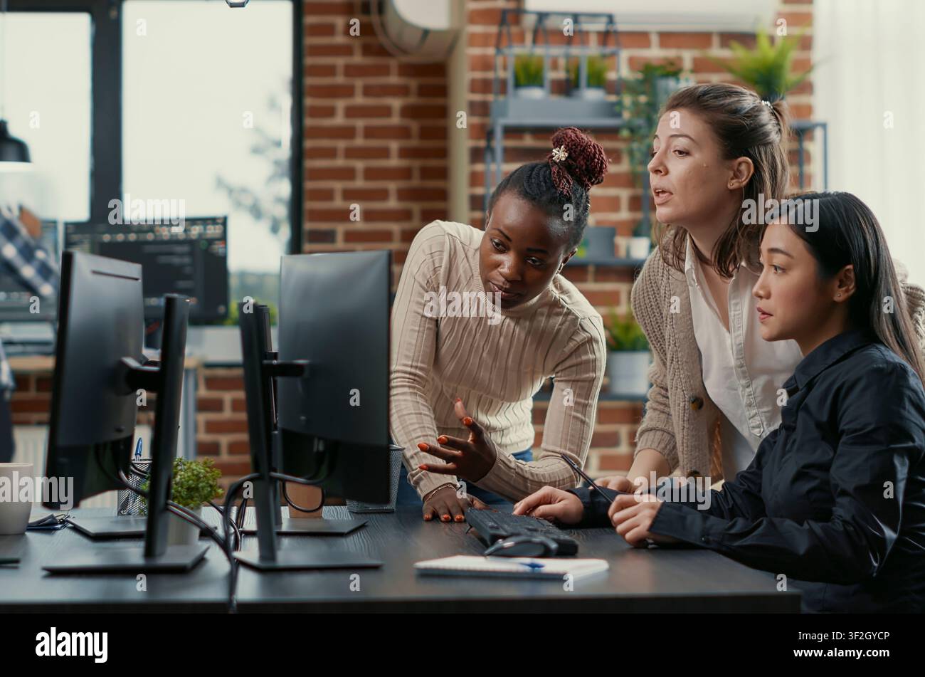 Programmers brainstorm new code library while a developer team discusses algorithms, database work and new software ideas across office computer screens. Stock Photo