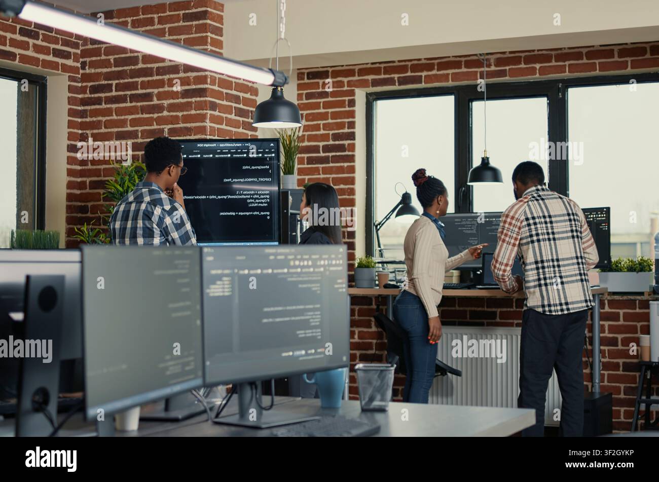 Developers review wall screen code errors as programmers review wall display errors, artificial intelligence code and collaborative debugging inside a software office. Stock Photo