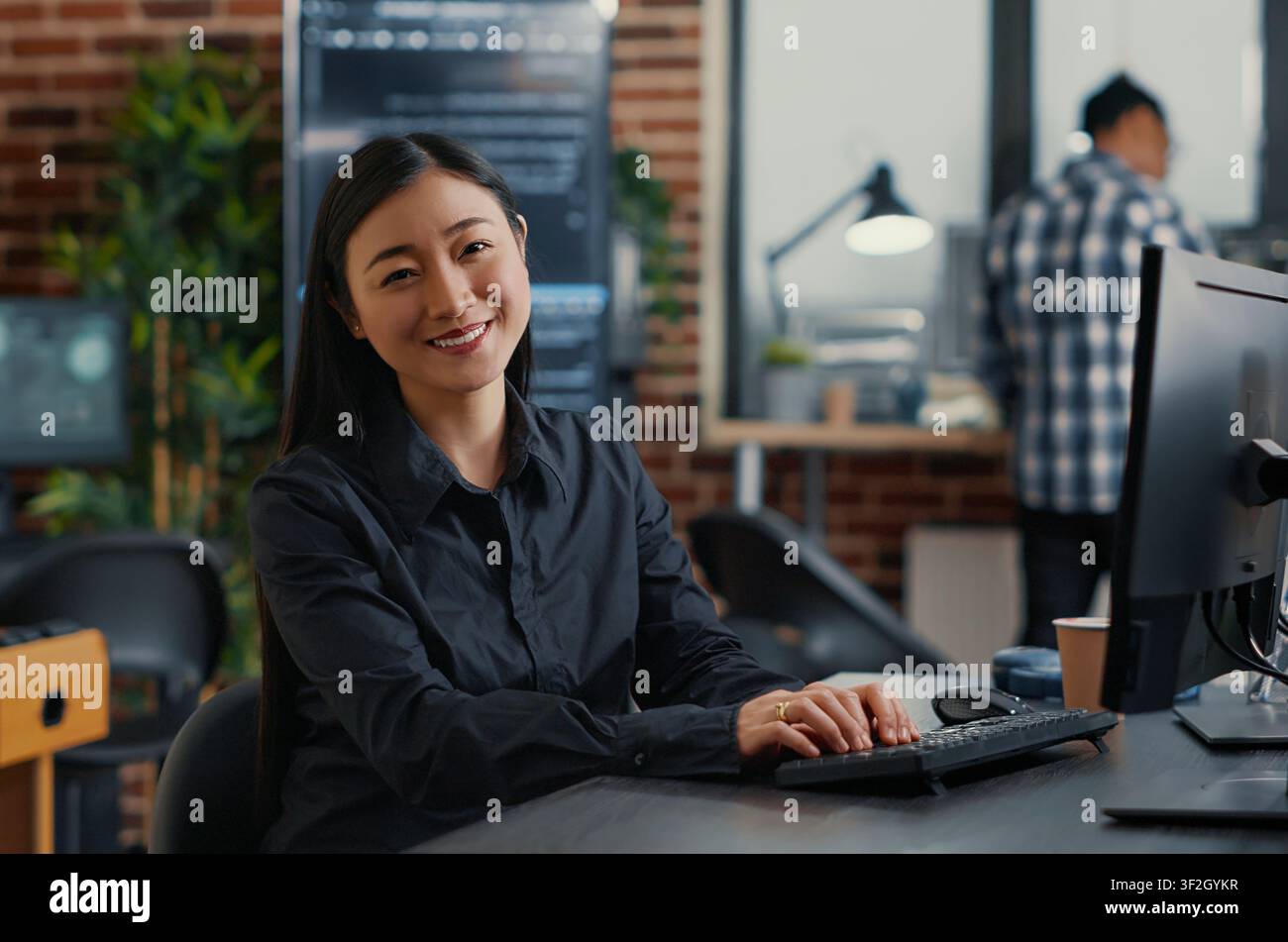 Asian software developer writes database code at a desk in a development agency, combining programming language, laptop coding and a confident technology portrait. Stock Photo