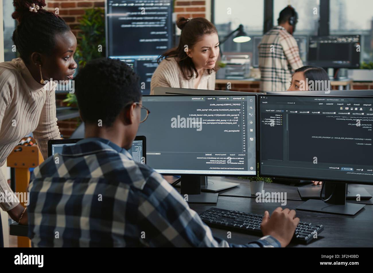 Mixed team of artificial intelligence cloud programmers talking about programming in front of multiple screens compiling code, programmers doing teamwork looking at machine learning algorithms. Stock Photo