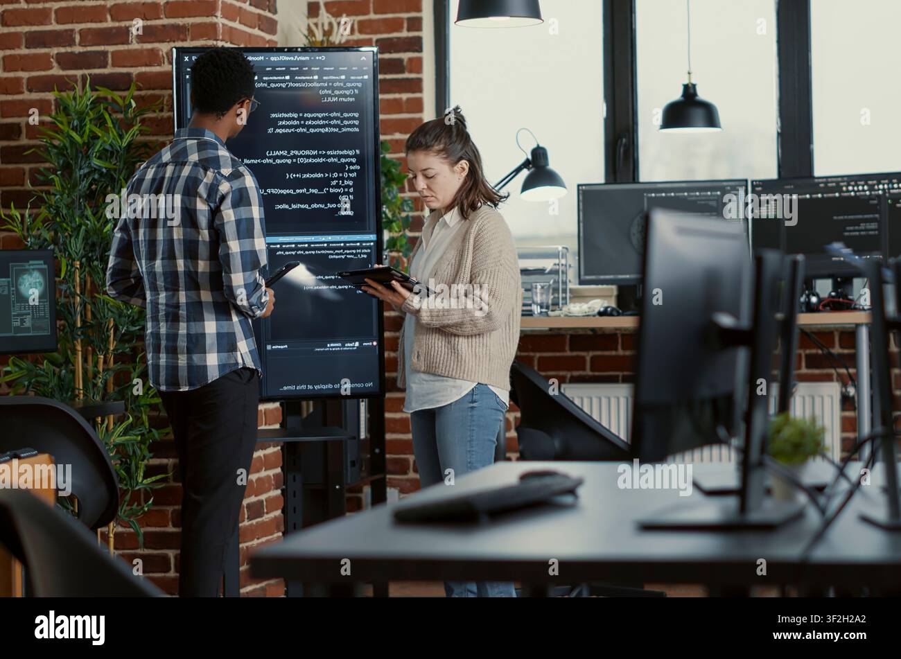 Developer presents code errors with tablet as engineers use a tablet and wall display to review bugs, cloud computing and team software development in an IT office. Stock Photo