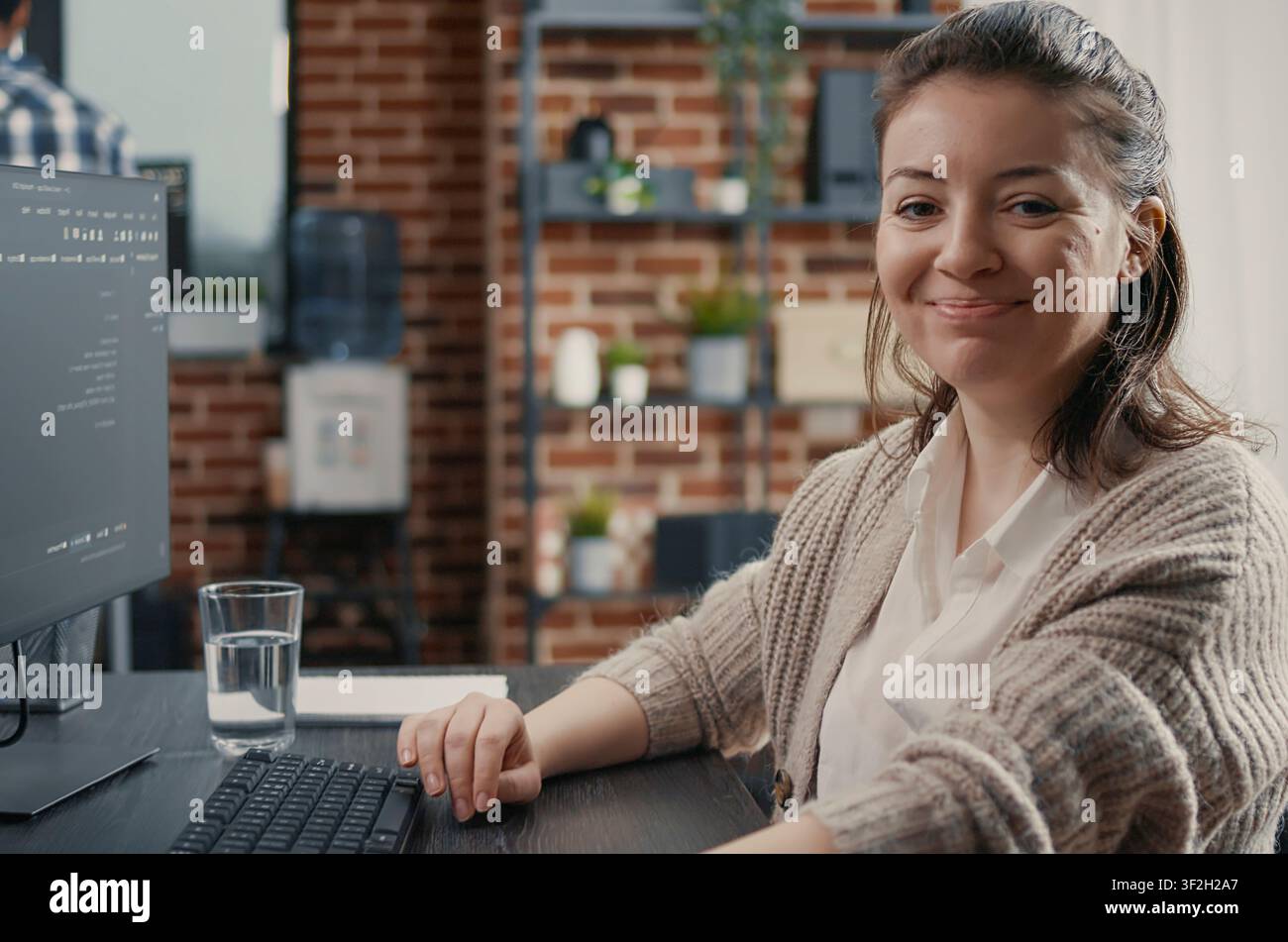 Smiling engineer types source code at a desk in a development agency, combining programming language, laptop coding and a confident technology portrait. Stock Photo