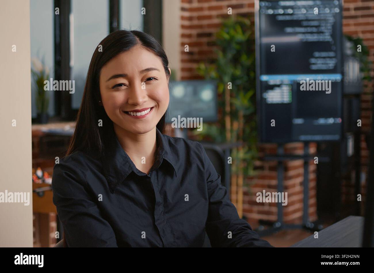 Smiling developer typing machine learning code at desk while developers work with code, terminal windows and digital systems in an IT office focused on software production. Stock Photo
