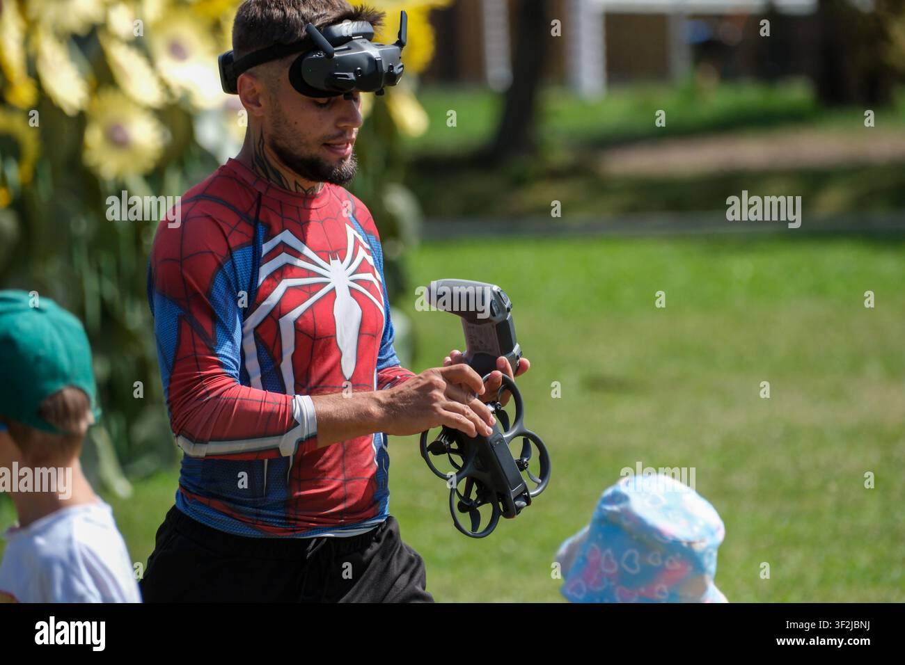 Kyiv, Ukraine - July 17, 2026: An FPV drone pilot wearing video goggles prepares a quadcopter for flight while holding a remote controller during an o Stock Photo