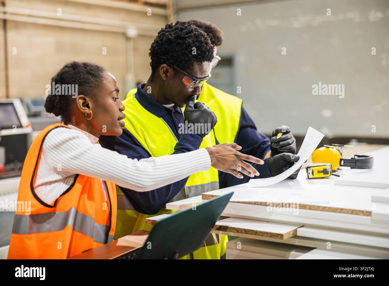 Factory workers collaborating on project blueprints at lumberyard Stock Photo
