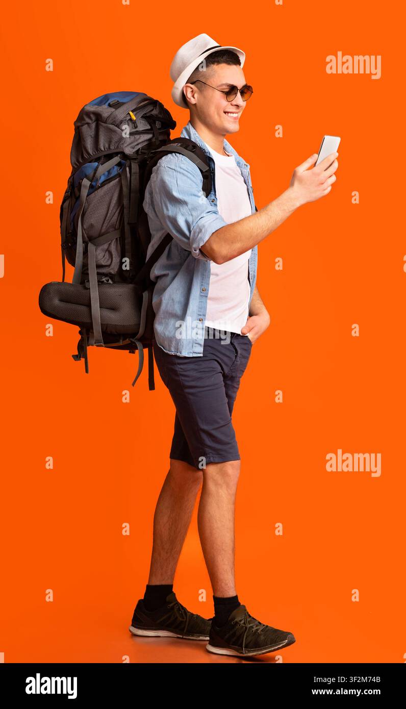 Hiker using trekking app on mobile phone over orange background Stock Photo