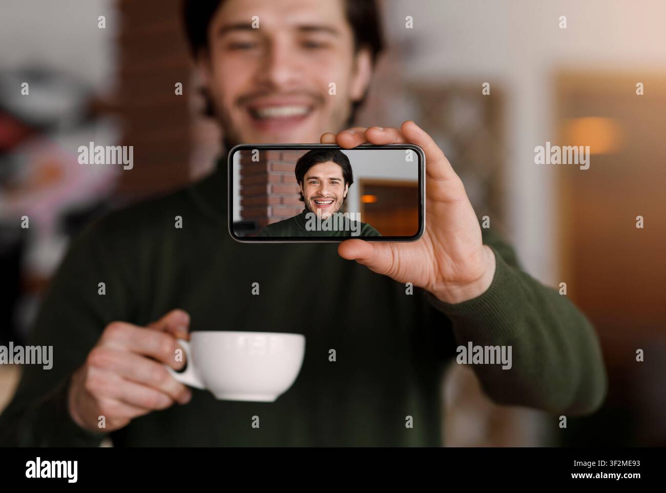 Young handsome man taking selfie while drinking coffee Stock Photo