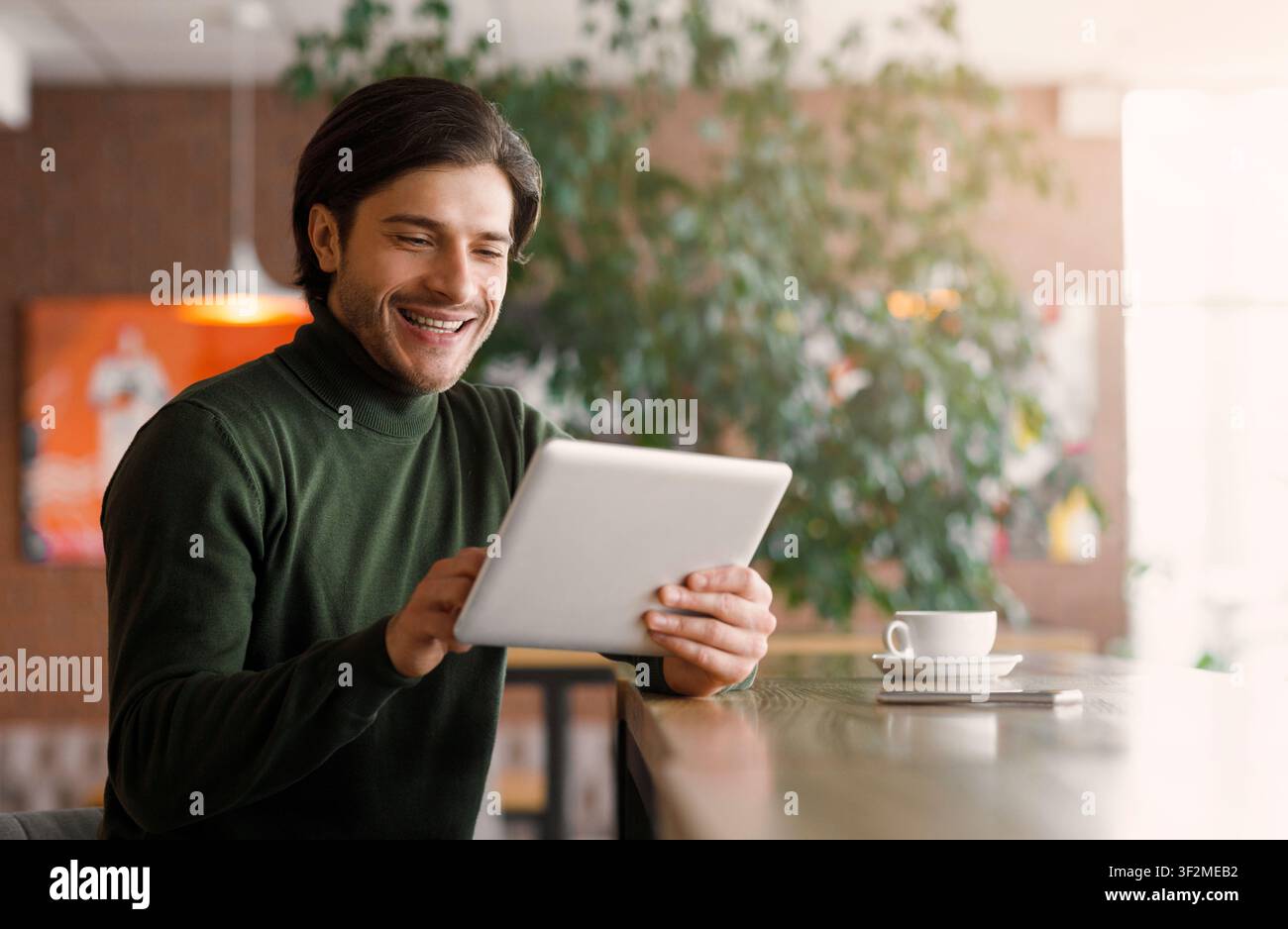 Joyful businessman using digital tablet at modern cafe Stock Photo
