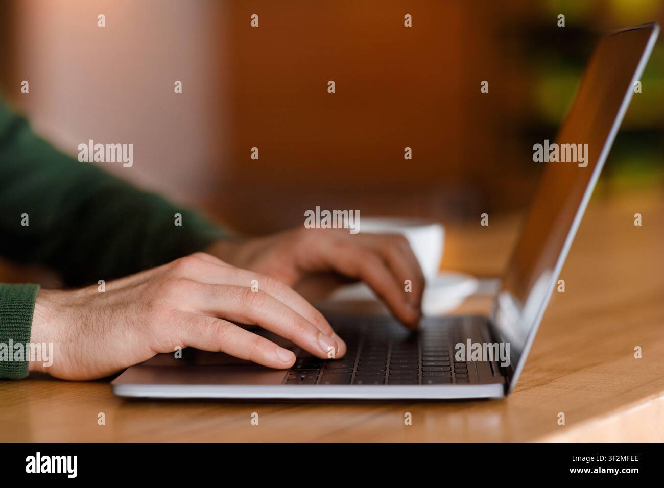 Freelancer hands typing on laptop keyboard, cafe interior Stock Photo