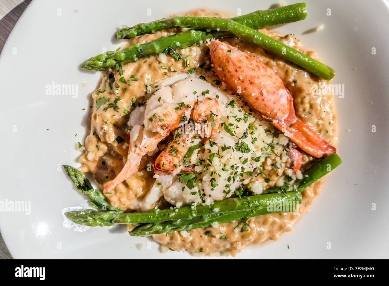 Lobster tail and claw meat on a creamy risotto with green asparagus, served in a restaurant on Peggy’s Cove Road in the Halifax Regional Municipality, Nova Scotia, Canada. Lobster from the North Atlantic is a staple of the cuisine along the South Shore. Halifax Regional, Nova Scotia, Canada Stock Photo