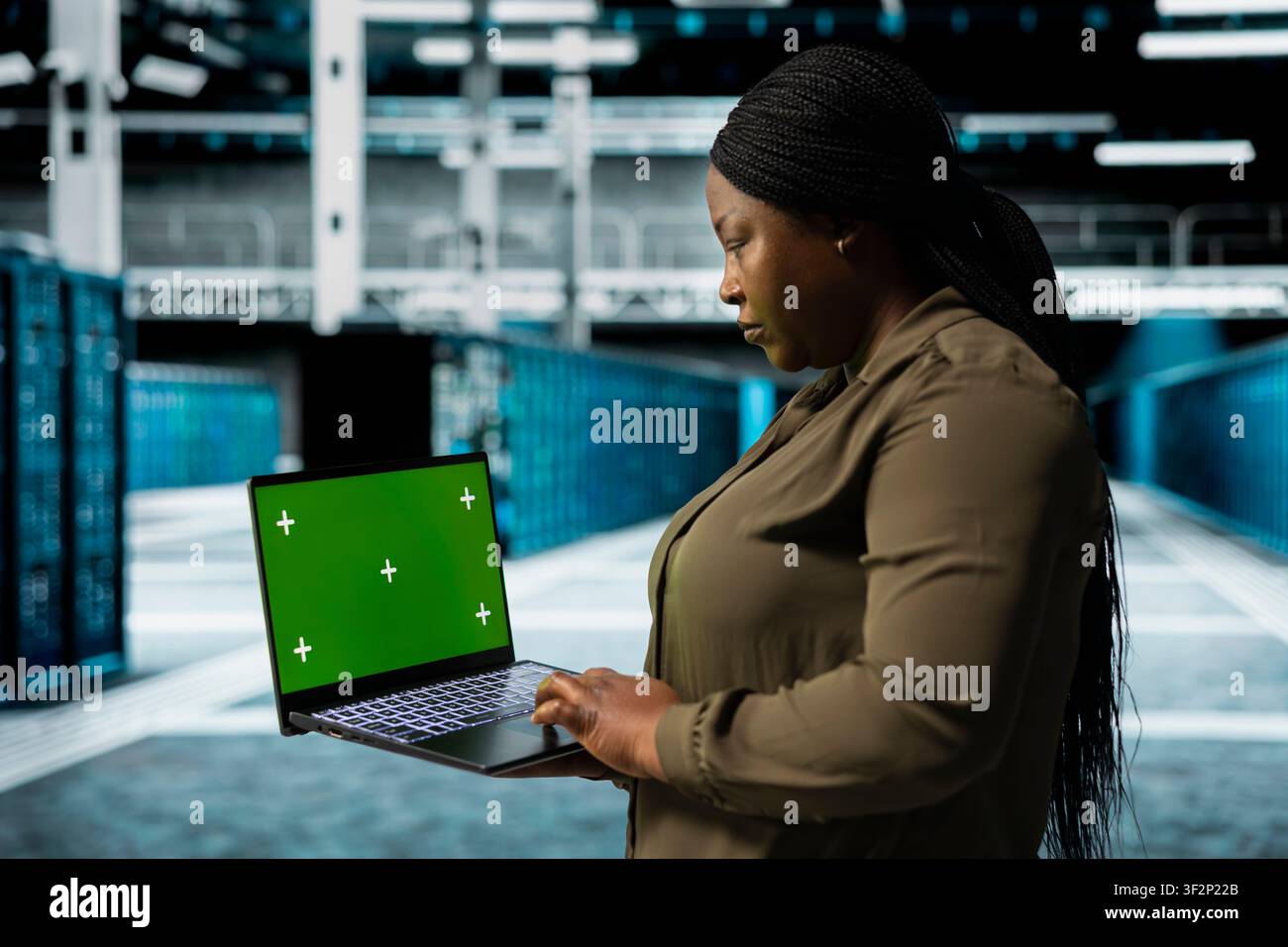 Developer holding isolated screen laptop walking through server room rows with storage mainframes. Computer scientist using mockup notebook to inspect data center helping power internet services Stock Photo