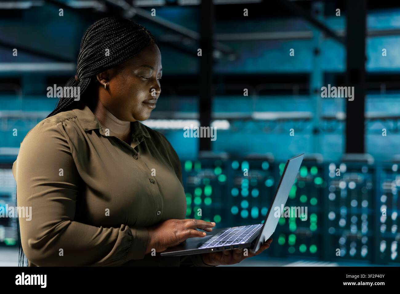 Software developer does maintenance on data center electronics processing large datasets. Server farm IT expert does backups on laptop to protect equipment used by cloud storage hosting companies Stock Photo