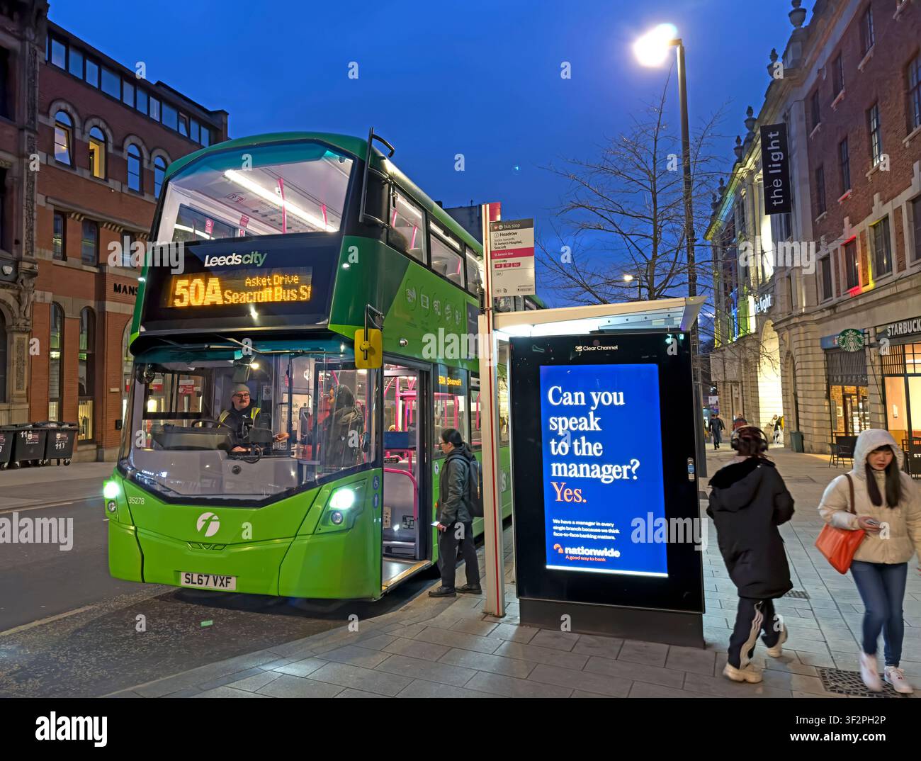 First Leeds 50A bus for Asket Drive boarding passengers on The Headrow in Leeds city centre during the blue hour at dusk Stock Photo