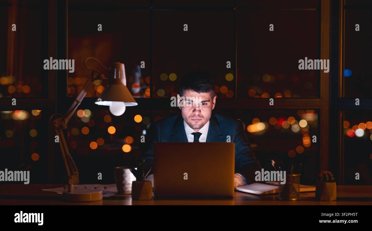 Entrepreneur Guy Working On Laptop Overnight In Modern Office, Panorama Stock Photo