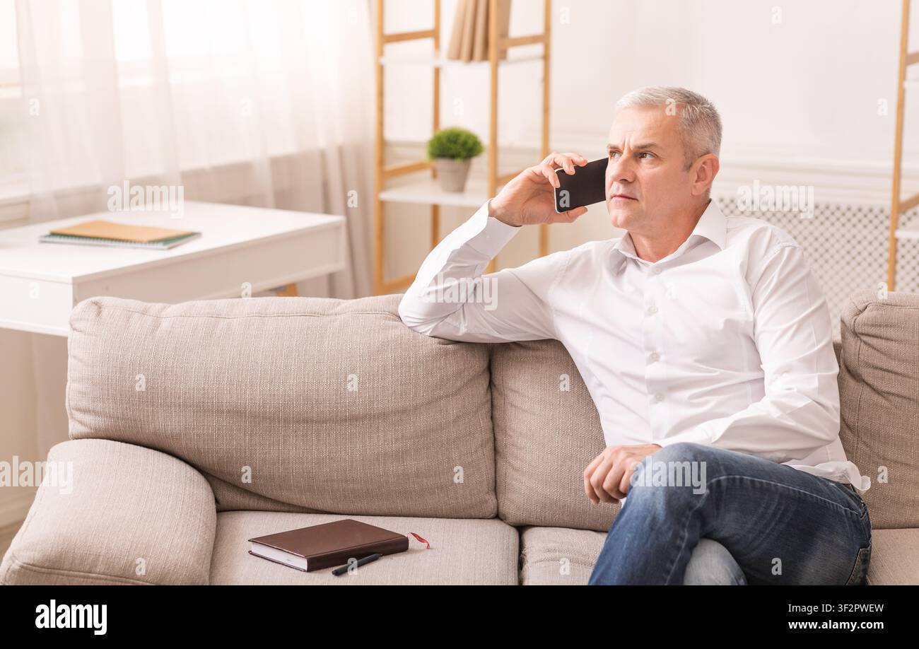 Senior man talking on mobile phone at his home Stock Photo
