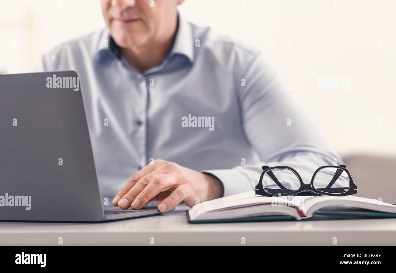 Unrecognizable middle aged man using laptop at home Stock Photo