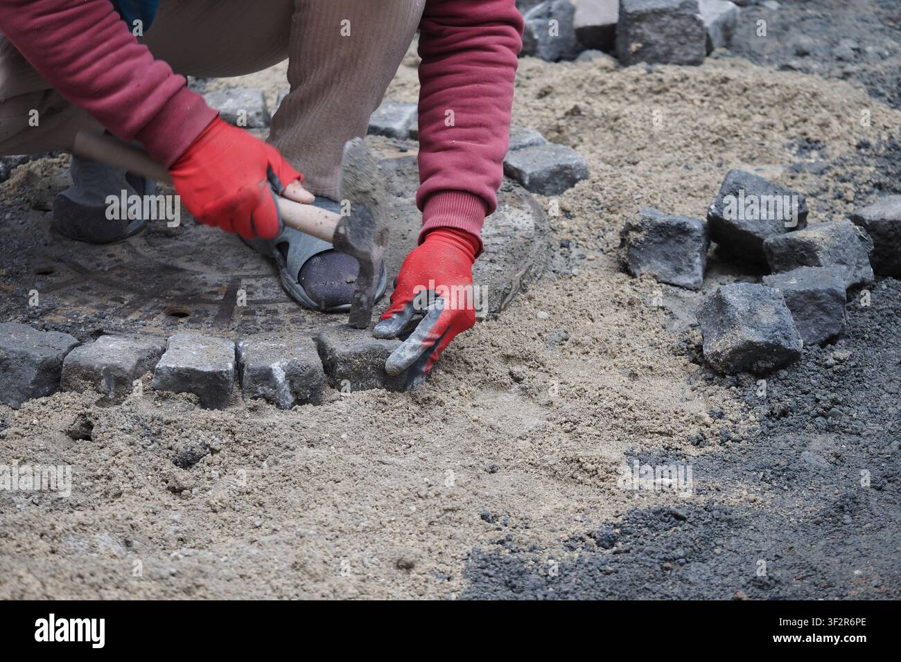 Person laying bricks on a construction site in daylight Stock Photo