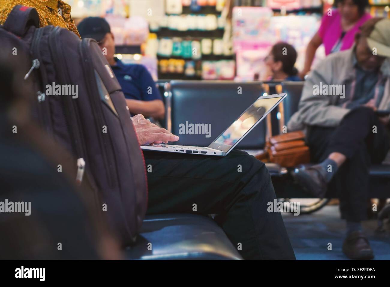close up of man working on laptop computer while waiting in the airport terminal Stock Photo