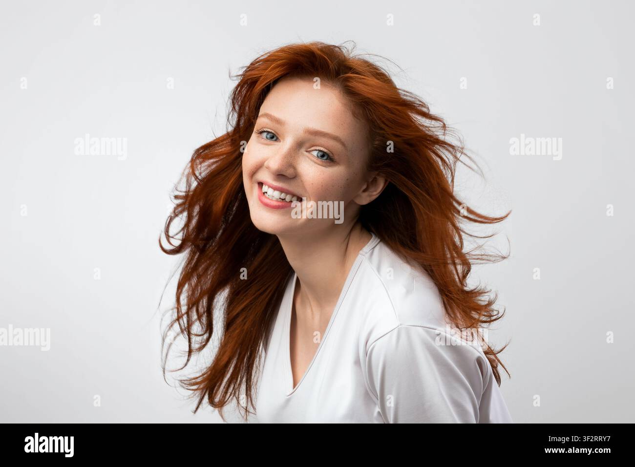 Headshot Of Smiling Red-Haired Young Female Over Gray Background Stock Photo